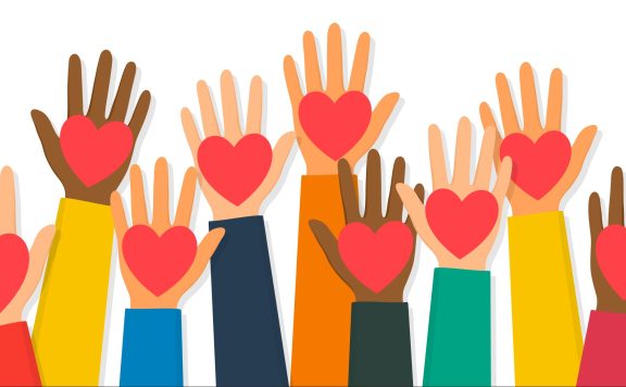 Charity, volunteering and donating concept. Raised up human hands with red hearts. Children’s hands are holding heart symbols